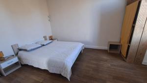 a bedroom with a white bed and a wooden floor at Les Tournesols in Égletons