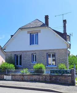 a stone house with blue windows on a street at Les Tournesols in Égletons
