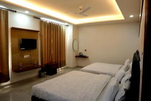 a hotel room with two beds and a television at Hotel Maurya Greens in Banbāsa
