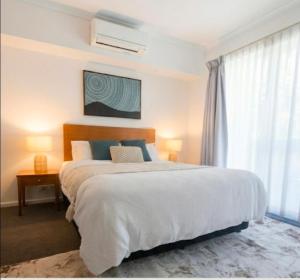 a bedroom with a large white bed and a window at Cozy water side apartment - Jetty in Mandurah