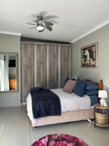 a bedroom with a bed and a ceiling fan at Peace Lily Garden Cottage in George +15 photos