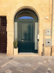 a green door in a stone building with a potted plant at La Suite di Martina in Lecce
