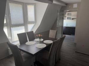 a dining room with a table and chairs and a kitchen at Lenti Central Apartman in Lenti
