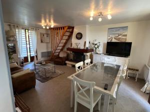 a living room with a dining room table and a staircase at Maison Vexin in Boury-en-Vexin