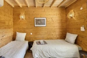 two beds in a room with wooden walls at Le Pech Eternel-Lodge Spa Tilleuls in Sarlat-la-Canéda