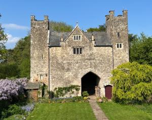 an old stone building with a gate in a yard at Welsh Gatehouse A Historic Castle Retreat that Welcomes Dogs and Electric Vehicles in Mathern