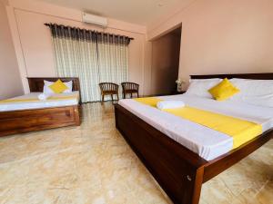 a bedroom with two beds and two chairs in it at Nature's Crest Resort in Urulewatta