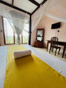 a bedroom with a large bed with a yellow blanket at Nature's Crest Resort in Urulewatta