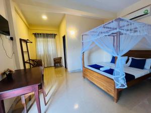 a bedroom with a canopy bed and a dining table at Nature's Crest Resort in Urulewatta +1 photo