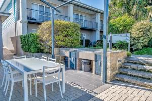 a table and chairs on a patio in front of a building at Cozy water side apartment - Jetty in Mandurah