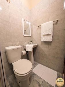 a bathroom with a toilet and a sink with towels at Nhacuene's place in Vilanculos
