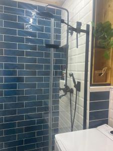 a shower in a bathroom with a blue tile wall at Mazury Czerwony Domek Jacuzzi in Romany +34 photos