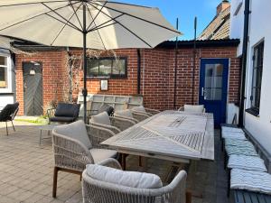 a patio with a table and chairs and an umbrella at Hotell Bäckagården in Ystad