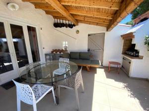 a patio with a glass table and chairs and a couch at Mas de la Vieille Vigne in Argelès-sur-Mer