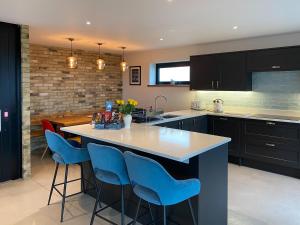 a kitchen with a large island with blue bar stools at Glenvar in Falmer