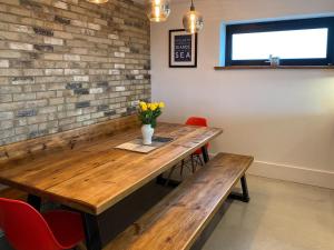 a dining room with a wooden table and red chairs at Glenvar in Falmer