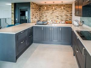 a kitchen with black cabinets and a brick wall at Glenvar in Falmer