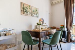 a kitchen with a wooden table and green chairs at By Domy 2 Grottaglie in Grottaglie