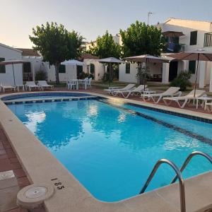 a large blue swimming pool with chairs and umbrellas at Apartamentos Surest in Cala en Blanes