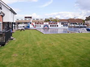 a large boat is docked next to a house at Pottergate Cottage in Wroxham +6 photos