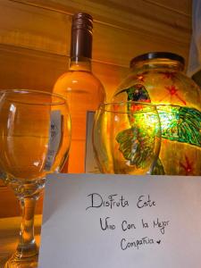 a bottle of alcohol and two glasses and a sign at Taida Chalet - Glamping in Villa de Leyva