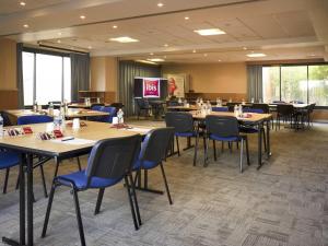 a conference room with tables and chairs and a screen at ibis Cannes Mandelieu in Mandelieu-La Napoule