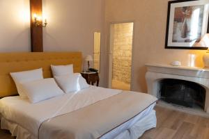 a bedroom with a white bed with a fireplace at BRIT HOTEL Le Lion d'Or CHINON in Chinon