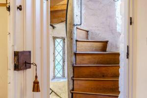 a door leading into a room with wooden stairs at Welsh Gatehouse A Historic Castle Retreat that Welcomes Dogs and Electric Vehicles in Mathern