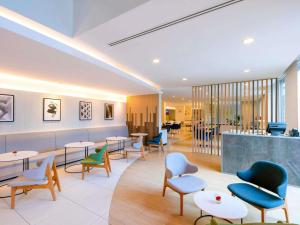 a waiting room with tables and chairs and a bar at ibis Bangkok Sathorn in Bangkok