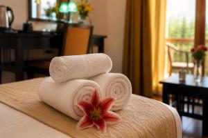 a pile of towels on a table with a flower at The Apricot Tree Hotel in Nūrla