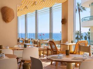 a restaurant with tables and chairs and a view of the ocean at Mercure Nice Promenade Des Anglais in Nice