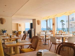 a restaurant with tables and chairs with the ocean in the background at Mercure Nice Promenade Des Anglais in Nice