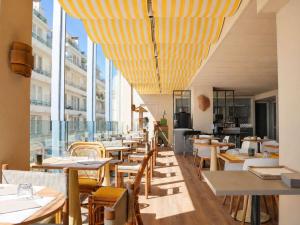 a restaurant with tables and chairs and large windows at Mercure Nice Promenade Des Anglais in Nice +40 photos