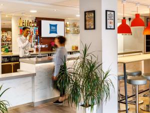 two people standing at a counter in a bar at ibis budget Leicester in Leicester
