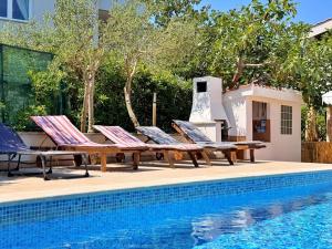 a group of lounge chairs and a swimming pool at Apartments Zeljko B in Šilo