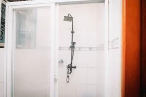 a shower in a bathroom with a white tiled wall at Kampala Kolping Hotel in Kampala +13 photos