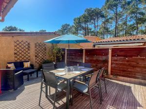 a table with chairs and an umbrella on a deck at Palombes 5 in Lacanau
