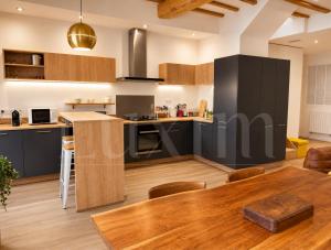 a kitchen with black cabinets and a wooden table at Le Cocon de la Presqu'île in Lyon +2 photos
