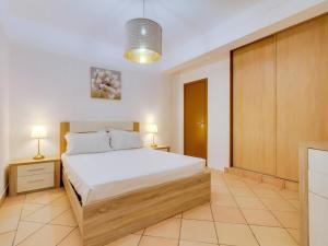 a bedroom with a bed and two lamps and a cabinet at Vale do Farol Cozy Retreat in Quarteira