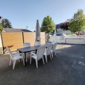 a table with white chairs and an umbrella and a fence at Chez Albert au bord de plage in Cherrueix