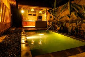 a pool of green water in a backyard at night at Rise Simpangan Villa in Payangan