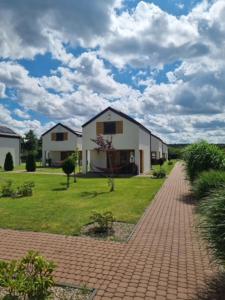 a house on a field with a brick walkway at Domki Lawendowe in Łeba
