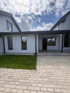 a white house with a driveway in front of it at Jasmine Guest Room in Jauntīreļi