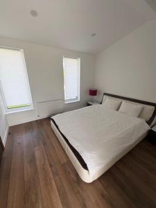 a white bedroom with a bed and two windows at Jasmine Guest Room in Jauntīreļi