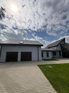 a white building with two garage doors and a cloudy sky at Jasmine Guest Room in Jauntīreļi