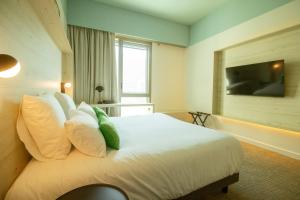 a bedroom with a bed with white pillows and a television at Ysotop Hôtel Grenoble in Grenoble