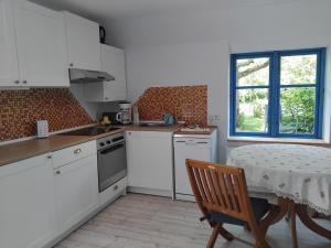 a kitchen with white cabinets and a table and a window at Ferienhof - Rauhenberg in Wangels