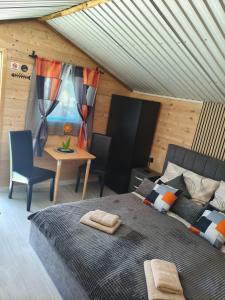 a bedroom with a bed and a table and a desk at Fenyőházak in Buzsák +10 photos