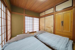 a bedroom with a bed in a room with windows at 民泊ａｉｋｏ in Fukushima