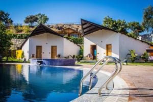 a swimming pool in front of a house at Bamboo Saa Resort & Spa - Udaipur in Udaipur